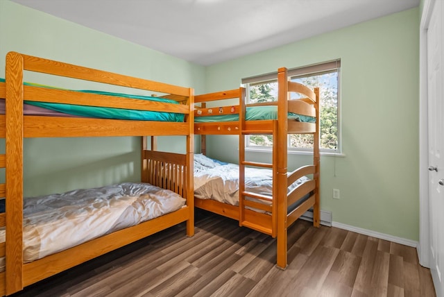 bedroom featuring baseboard heating, wood finished floors, and baseboards