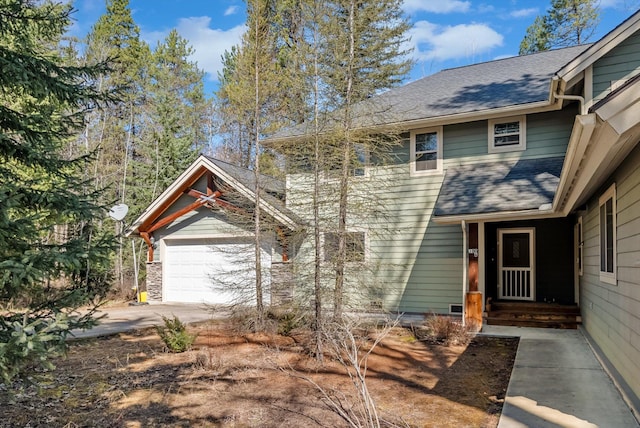 view of front of property featuring driveway, a shingled roof, and an attached garage