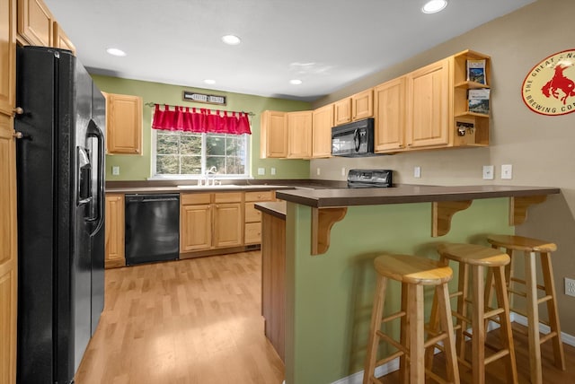 kitchen with black appliances, light wood-style floors, light brown cabinets, and a peninsula