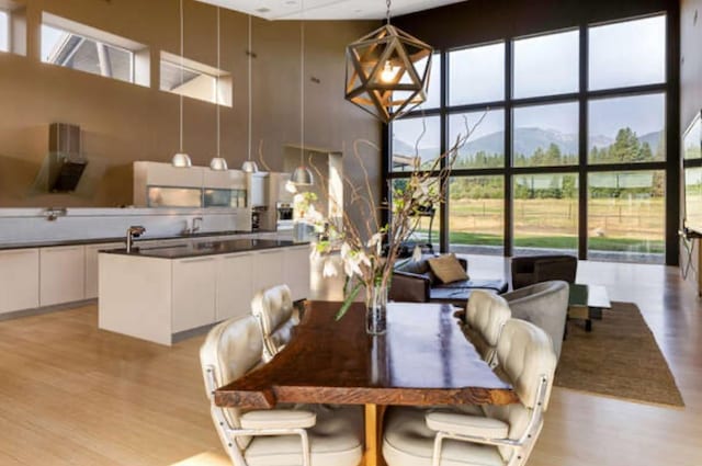 dining room with a towering ceiling, light wood-type flooring, and a mountain view