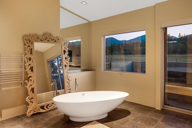 bathroom with a soaking tub, radiator, a mountain view, and tile patterned flooring