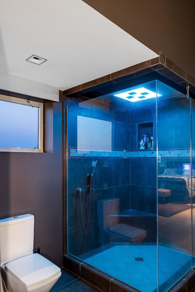 bathroom featuring a stall shower, toilet, and tile patterned floors