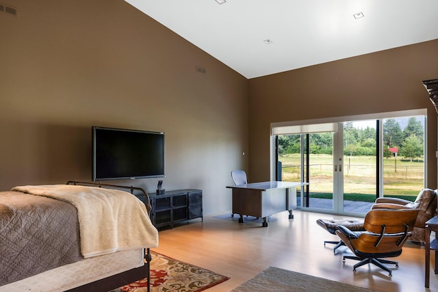 bedroom featuring high vaulted ceiling, access to exterior, and wood finished floors