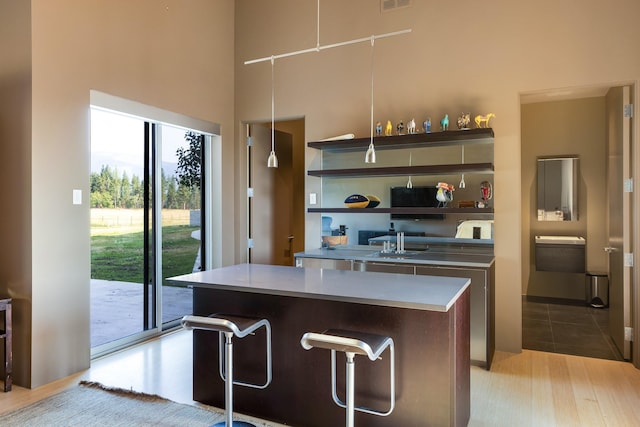 kitchen with a center island, a high ceiling, open shelves, a kitchen bar, and light countertops