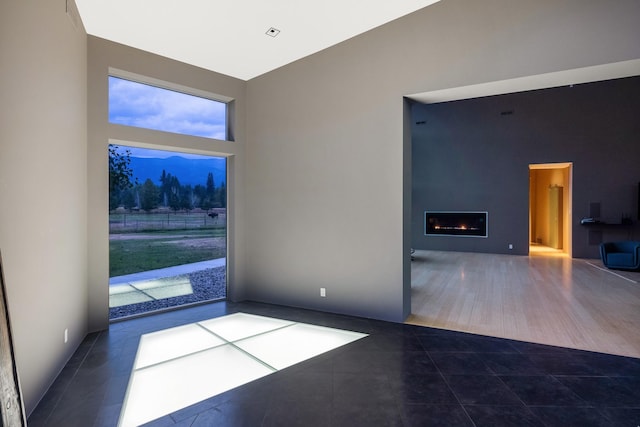 unfurnished room featuring tile patterned floors and a glass covered fireplace