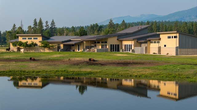 back of house featuring a wooded view and a water and mountain view