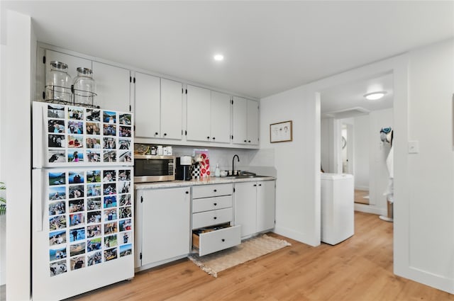 648 7th Ave W, Kalispell, MT 59901 - kitchen with freestanding refrigerator, stainless steel microwave, light wood-style flooring, light countertops, and white cabinets