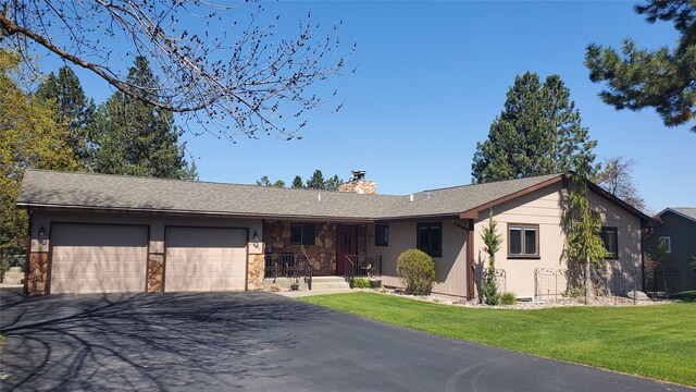 3208 Paul Ln, Missoula, MT 59803 - single story home with a chimney, aphalt driveway, stone siding, a front yard, and an attached garage