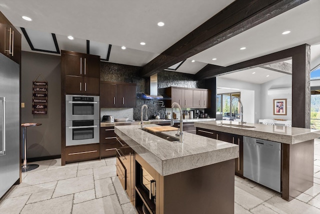 15 Copper Ridge Rd, Trout Creek, MT 59874 - kitchen featuring appliances with stainless steel finishes, a center island with sink, stone tile flooring, wall chimney range hood, and a sink