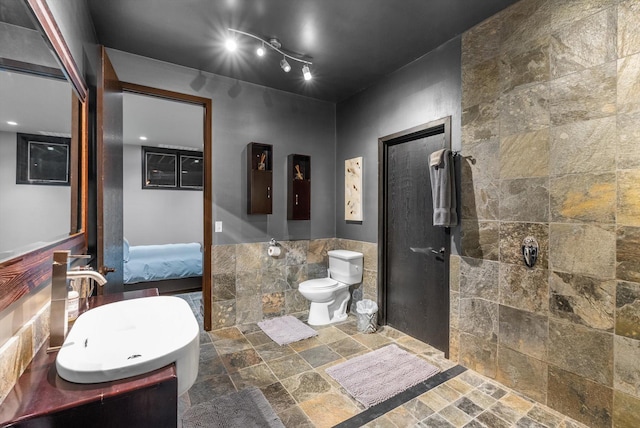 15 Copper Ridge Rd, Trout Creek, MT 59874 - full bath with stone tile flooring, connected bathroom, toilet, a tile shower, and tile walls