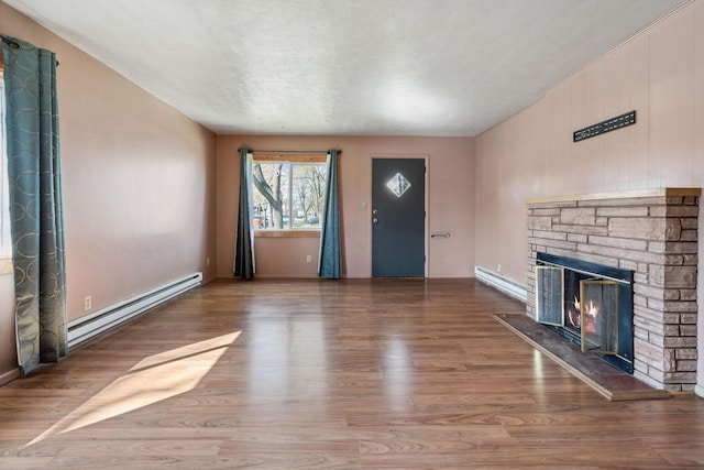 unfurnished living room with a glass covered fireplace, wood finished floors, and baseboard heating