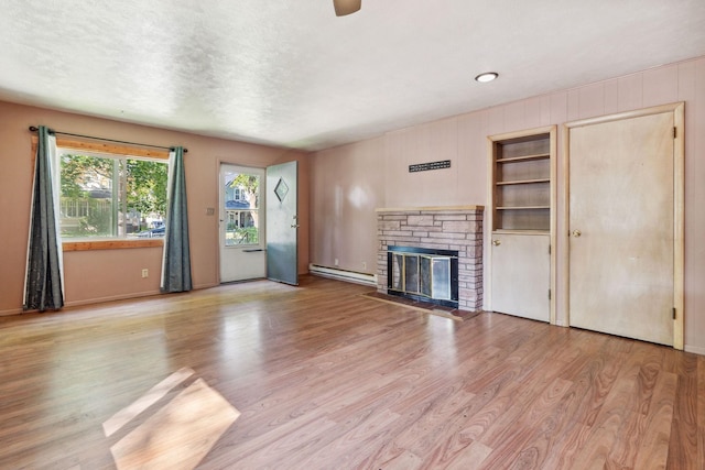 unfurnished living room with a fireplace, wood finished floors, a baseboard heating unit, and baseboards