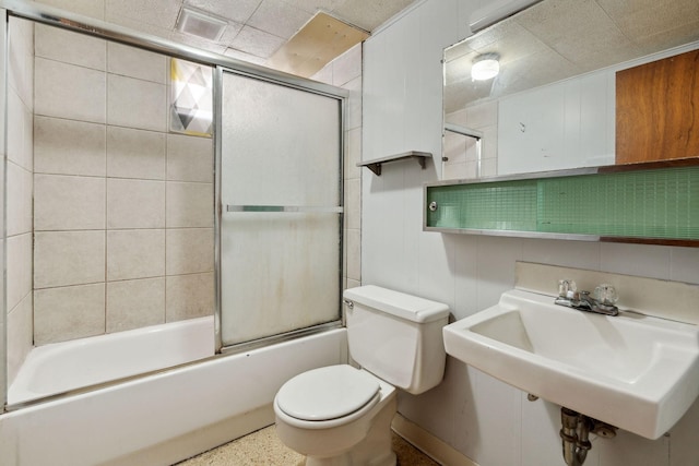 bathroom featuring enclosed tub / shower combo, toilet, visible vents, and a sink