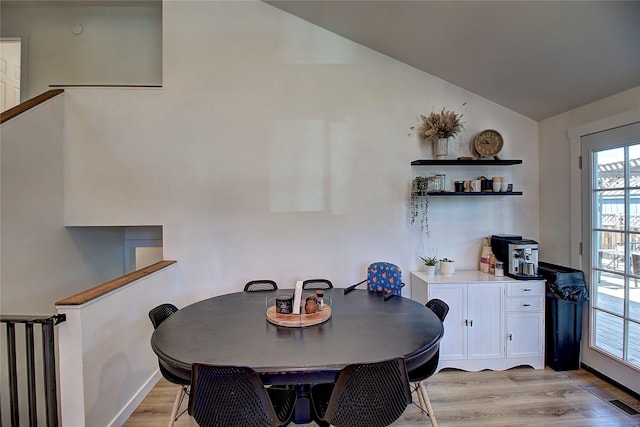 dining space featuring visible vents, a healthy amount of sunlight, lofted ceiling, and light wood finished floors