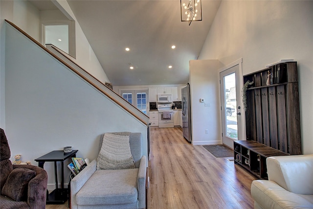 living room with stairway, baseboards, recessed lighting, light wood finished floors, and high vaulted ceiling