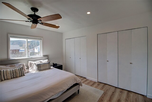 bedroom featuring recessed lighting, light wood-style flooring, ceiling fan, and two closets