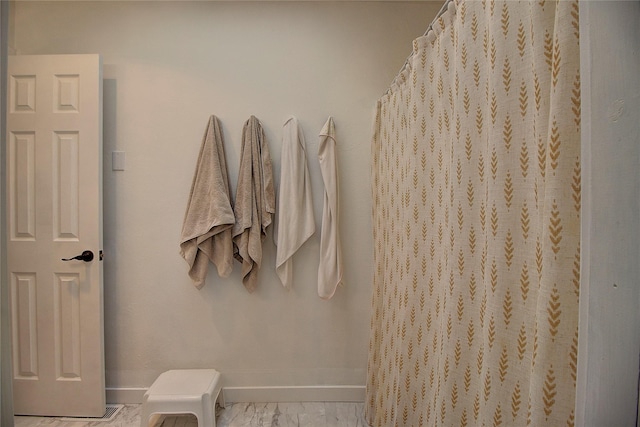 bathroom with curtained shower, marble finish floor, and baseboards