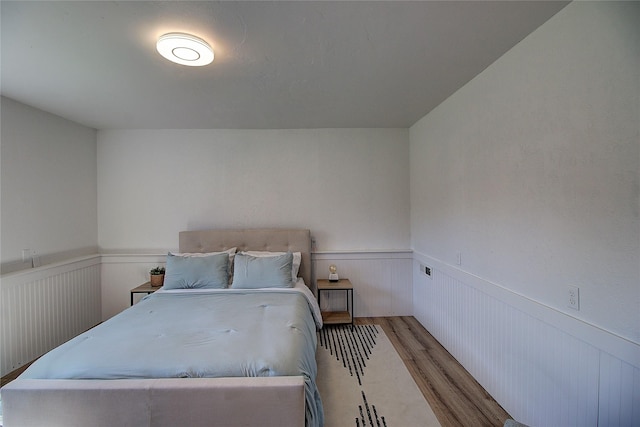 bedroom featuring wainscoting and wood finished floors