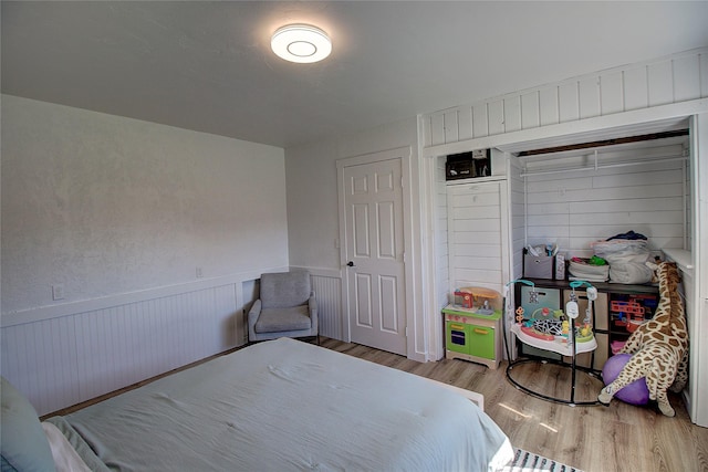 bedroom with a wainscoted wall and wood finished floors