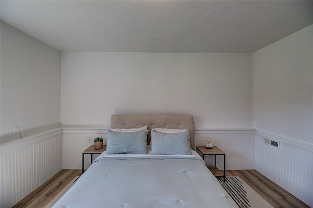 bedroom featuring wood finished floors and a wainscoted wall