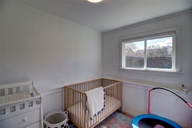 bedroom with wainscoting and a nursery area