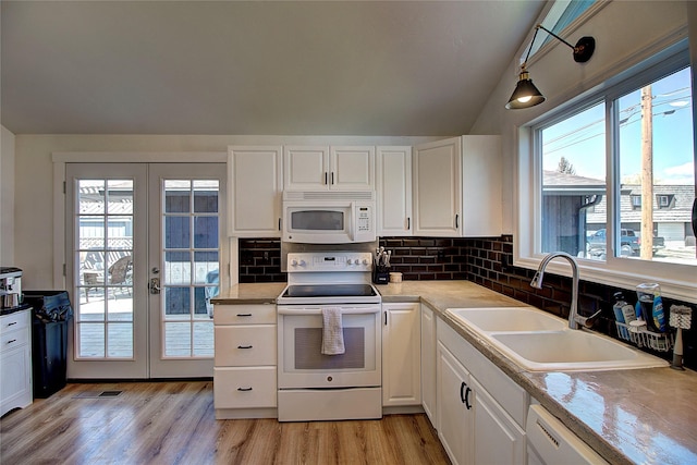 kitchen with lofted ceiling, french doors, white appliances, and a sink