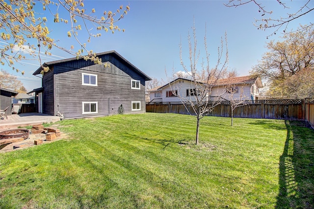 rear view of house with a lawn, a fire pit, and a fenced backyard