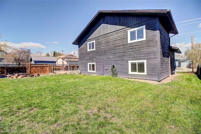 rear view of property featuring a lawn and fence
