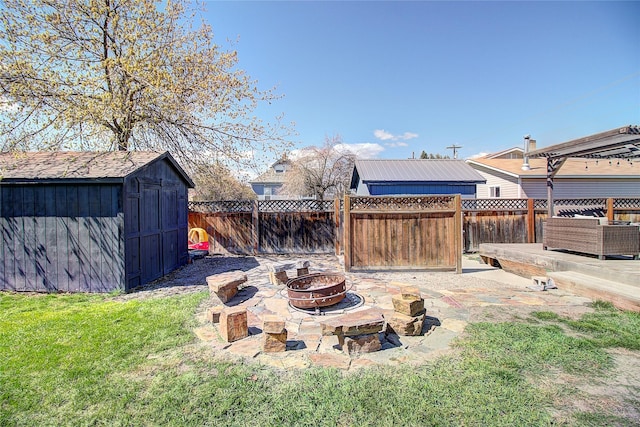view of yard featuring a fire pit, a storage unit, an outbuilding, and a fenced backyard