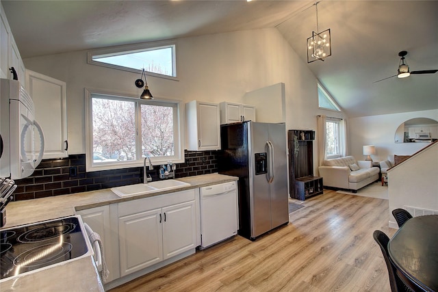 kitchen featuring white cabinets, white appliances, open floor plan, and a sink