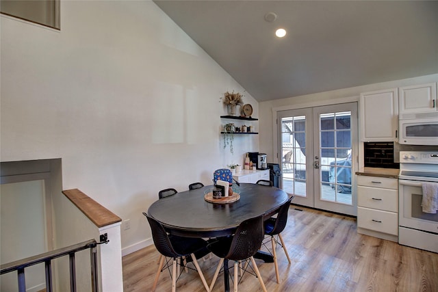 dining space with french doors, baseboards, vaulted ceiling, and light wood-style floors