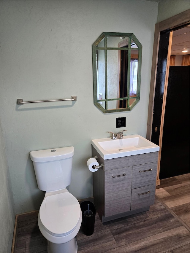 1512 Gaylord St, Butte, MT 59701 - half bathroom featuring toilet, vanity, wood finished floors, and baseboards