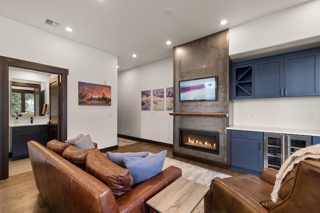 living room with recessed lighting, a large fireplace, a bar, visible vents, and beverage cooler