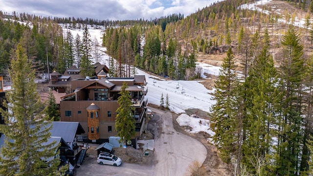 snowy aerial view with a wooded view