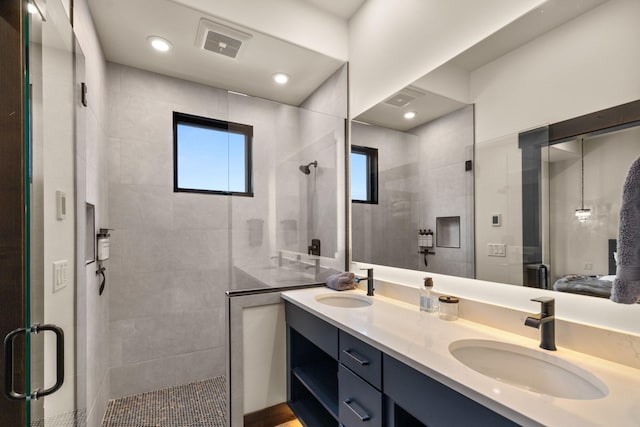 bathroom featuring double vanity, a sink, a shower stall, and visible vents