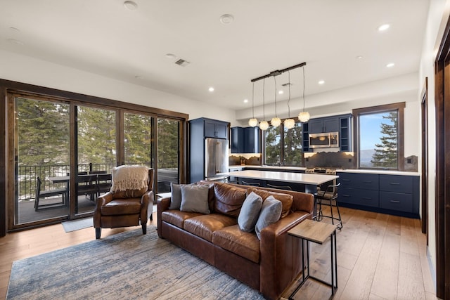 living area with light wood-type flooring, plenty of natural light, and recessed lighting