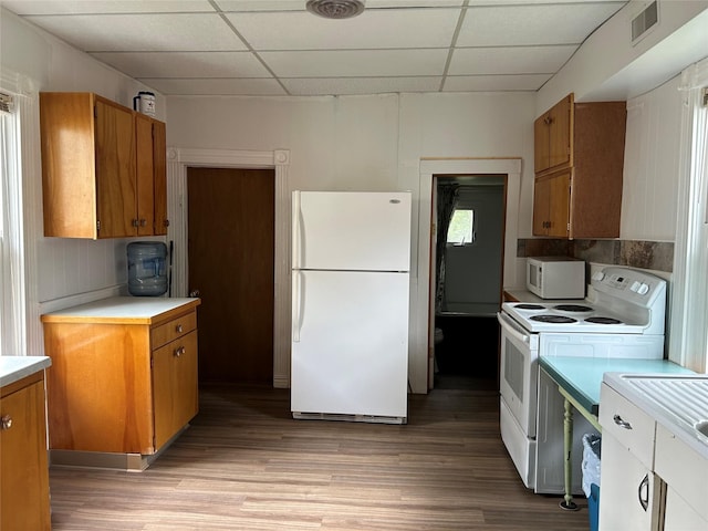 kitchen with light wood-style floors, brown cabinets, a drop ceiling, and white appliances