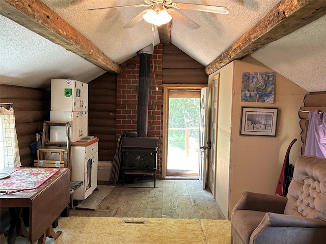 living area featuring a textured ceiling, rustic walls, hardwood / wood-style floors, and a wood stove