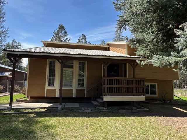 back of house with a porch, metal roof, and a yard