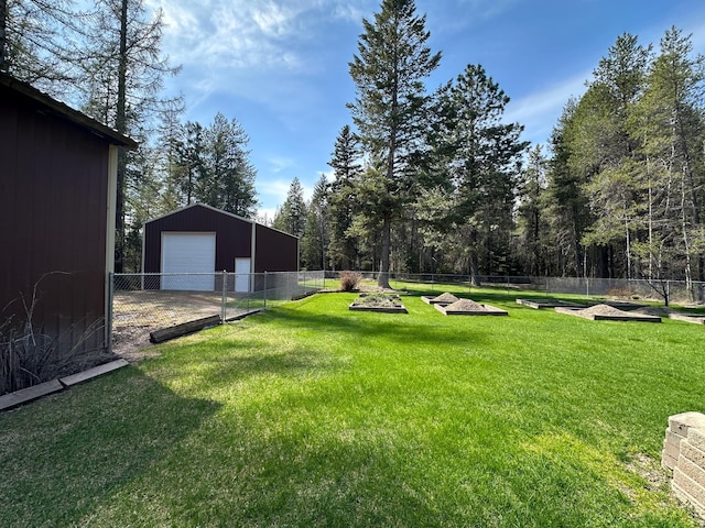 view of yard with driveway, an outdoor structure, a detached garage, fence, and a vegetable garden