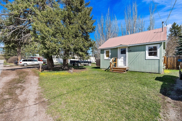 view of front of property featuring fence, a front lawn, and metal roof