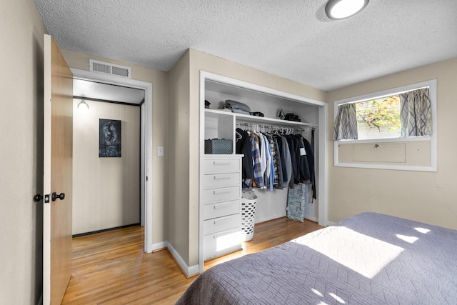 bedroom featuring a closet, visible vents, wood finished floors, and a textured ceiling