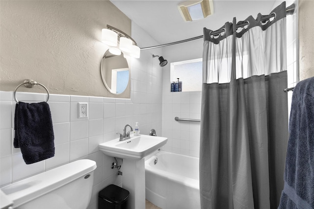full bath featuring toilet, shower / bath combination with curtain, and tile walls