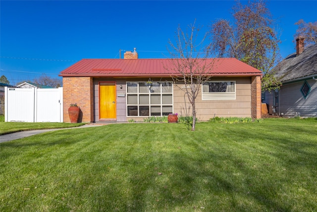view of front of property with metal roof, a front yard, fence, and a chimney