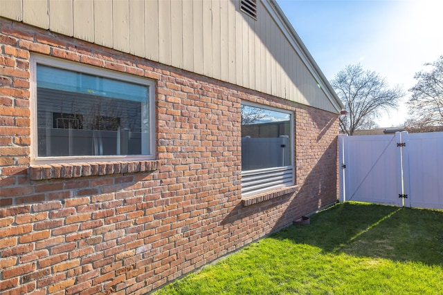 view of home's exterior featuring a yard, a gate, and brick siding