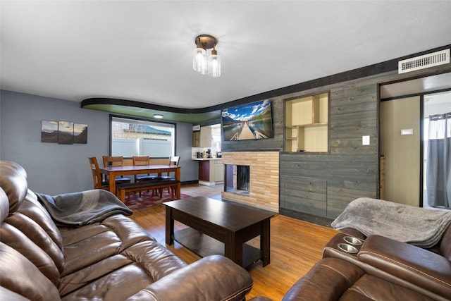 living room with visible vents, wood finished floors, a healthy amount of sunlight, and wood walls