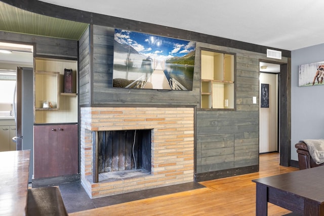 living area featuring visible vents, wood finished floors, and a fireplace