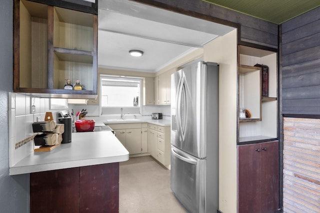 kitchen featuring open shelves, a sink, light countertops, ornamental molding, and stainless steel fridge