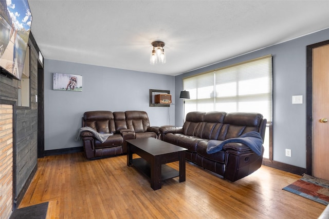 living area with wood finished floors, baseboards, and a brick fireplace
