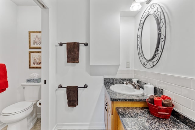 bathroom with toilet, vanity, and decorative backsplash